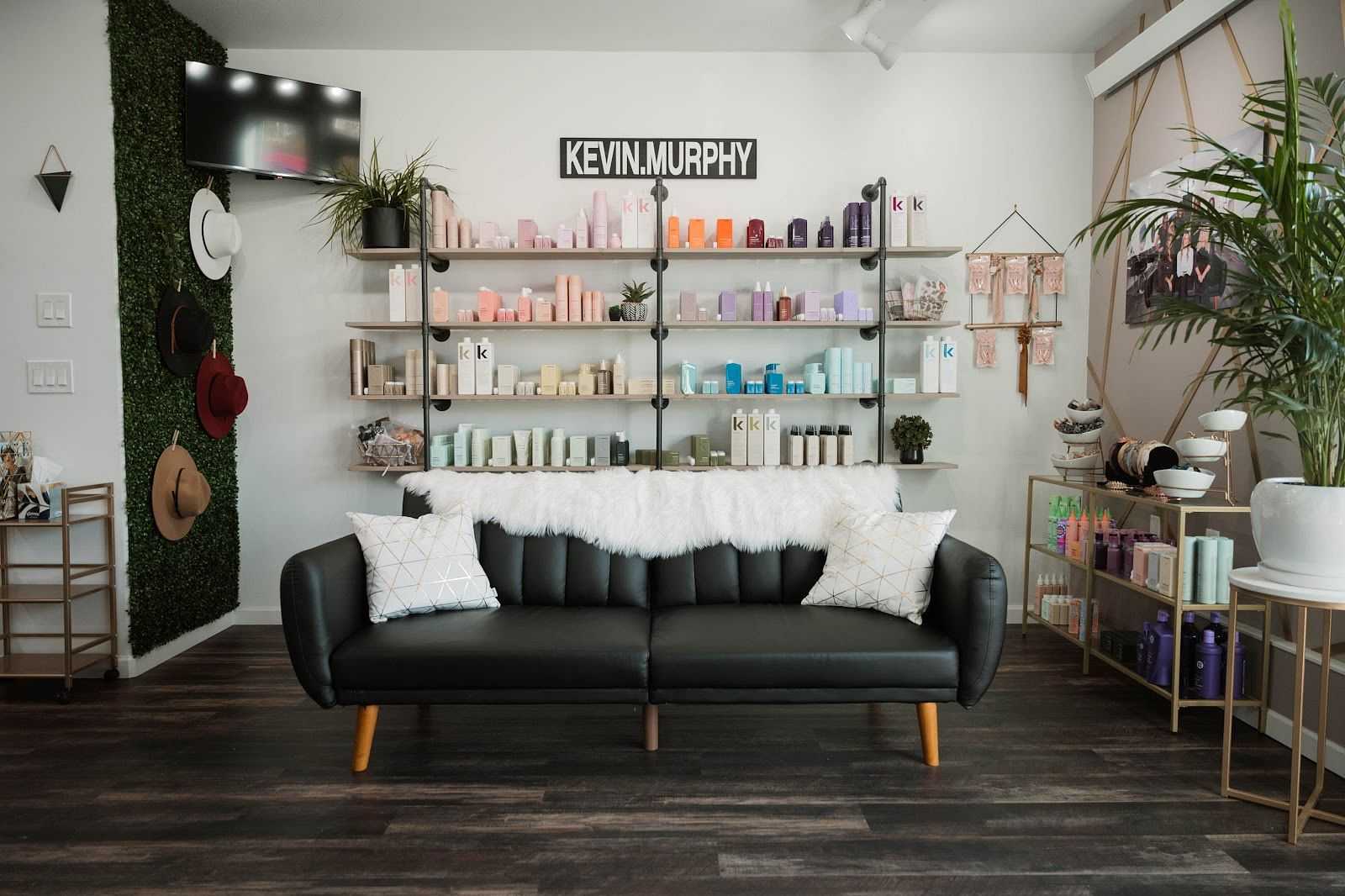 Modern salon with a stylish black sofa, neatly arranged shelves of hair products, and wall decor.